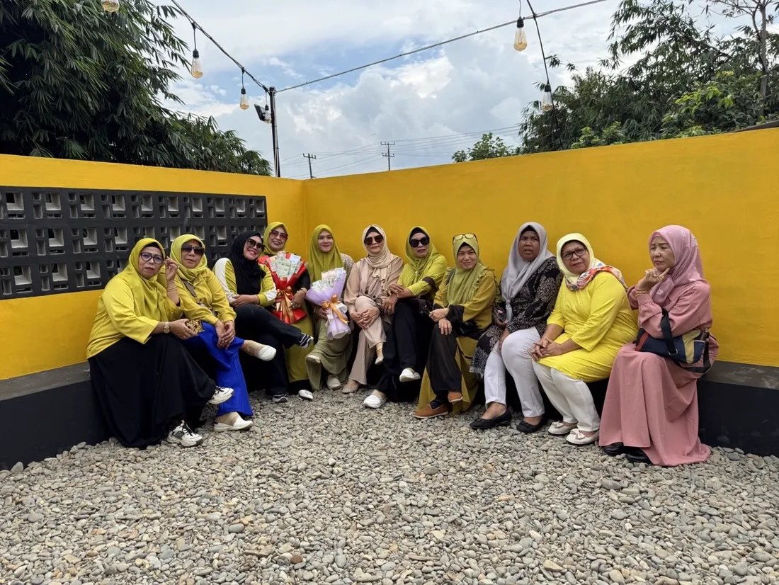 Ibu-ibu duduk berderet di area outdoor dinding kuning Jaikopi
